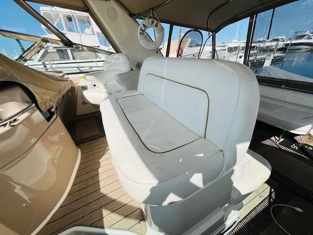 Slide: The Image of 1999 Sea Ray 400 Sundancer interior with white seating and marina view. - 11