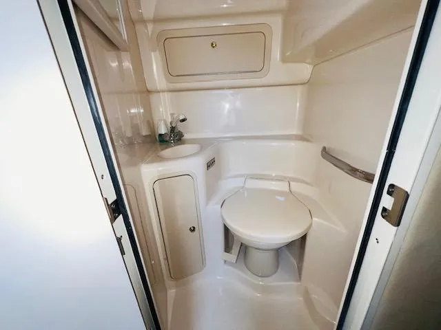 Slide: The Image of 1999 Sea Ray 400 Sundancer bathroom with compact design and white fixtures. - 23