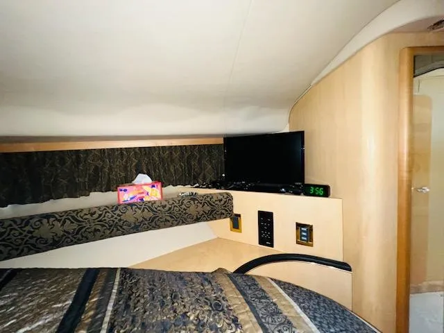 Slide: The Image of Interior cabin of 1999 Sea Ray 400 Sundancer with TV and patterned bedding. - 27