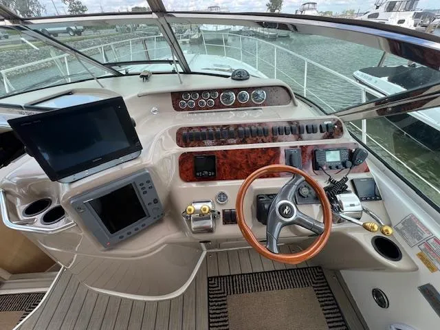 Slide: The Image of 1999 Sea Ray 400 Sundancer helm with navigation screens and steering wheel, docked by the water. - 7