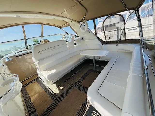Slide: The Image of 1999 Sea Ray 400 Sundancer interior with white seating and table, showcasing luxury yacht design. - 9
