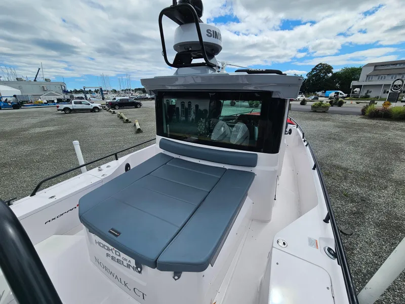 Slide: The Image of 2022 Axopar 28 boat with cushioned seating, docked in a marina. - 10