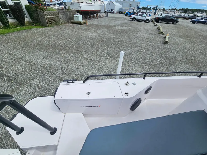 Slide: The Image of Axopar 28 boat, 2022 model, docked in a marina with parked cars and boats. - 11