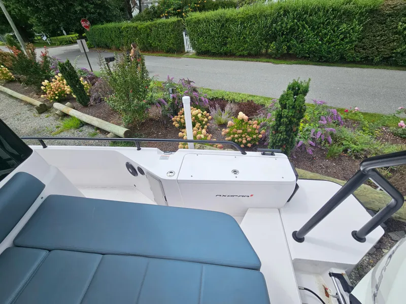 Slide: The Image of 2022 Axopar 28 boat with blue seating, parked near a garden. - 12