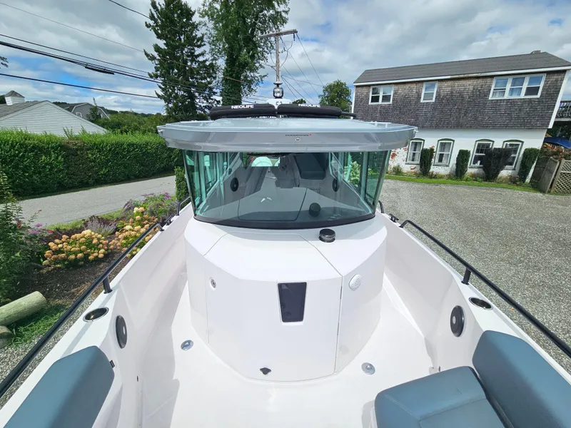 Slide: The Image of 2022 Axopar 28 boat with sleek design, docked near a house and garden. - 17