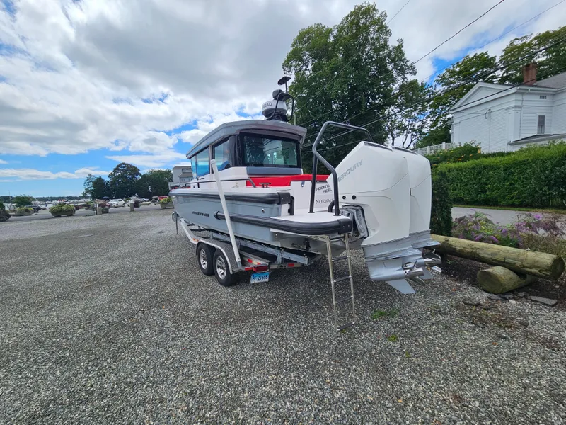 Slide: The Image of 2022 Axopar 28 boat on trailer, parked outdoors with cloudy sky. - 2