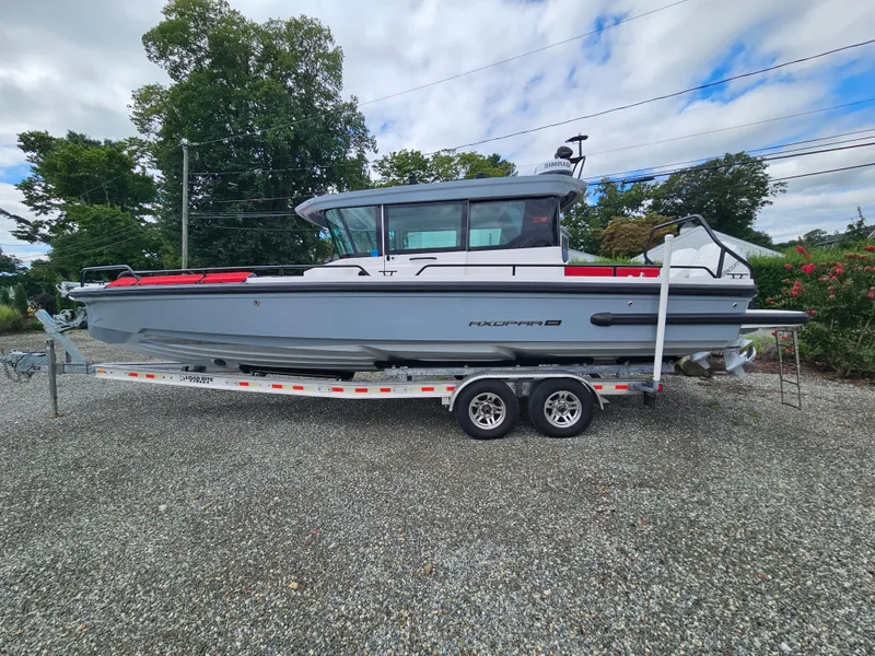 Slide: The Image of 2022 Axopar 28 boat on trailer, parked outdoors, with trees in the background. - 3