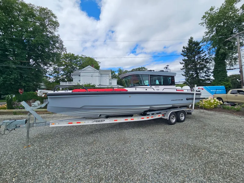 Slide: The Image of 2022 Axopar 28 boat on a trailer, parked outdoors on gravel. - 4