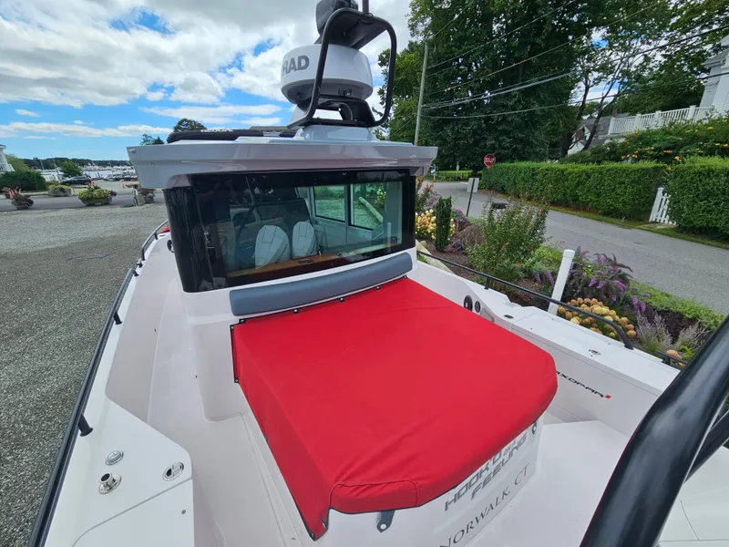 Slide: The Image of 2022 Axopar 28 boat with red cover, docked near lush greenery. - 7