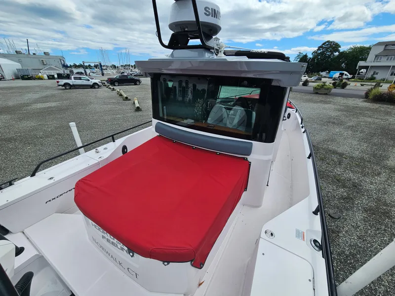 Slide: The Image of 2022 Axopar 28 boat with red seating, docked under a cloudy sky. - 8