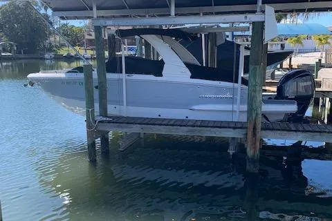 The Image of 2022 Chaparral 267 SSX OB boat docked on a lift in a marina. - 0