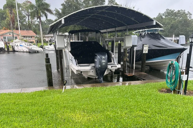 Slide: The Image of 2022 Chaparral 267 SSX OB boat docked under a canopy in a marina. - 11