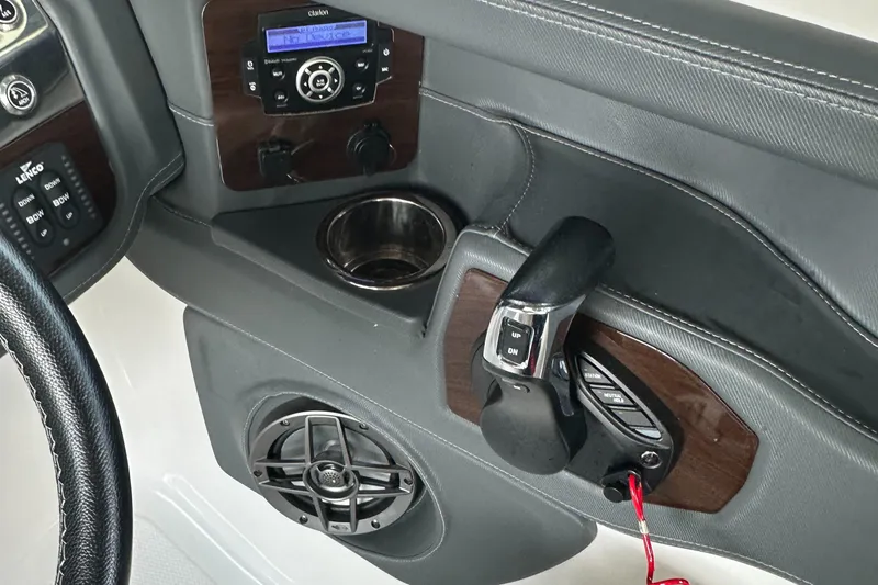 Slide: The Image of 2022 Chaparral 267 SSX OB boat dashboard with controls, cup holder, and speaker. - 27