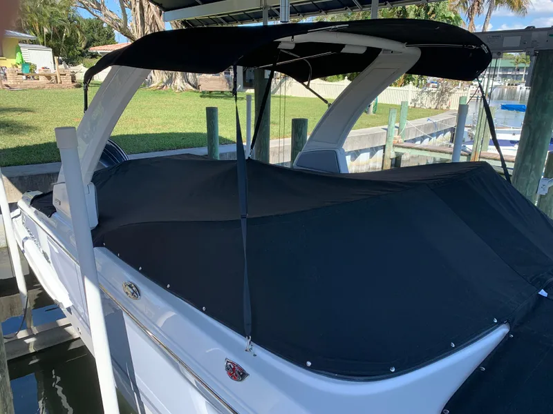 Slide: The Image of 2022 Chaparral 267 SSX OB boat with black cover docked in marina. - 3