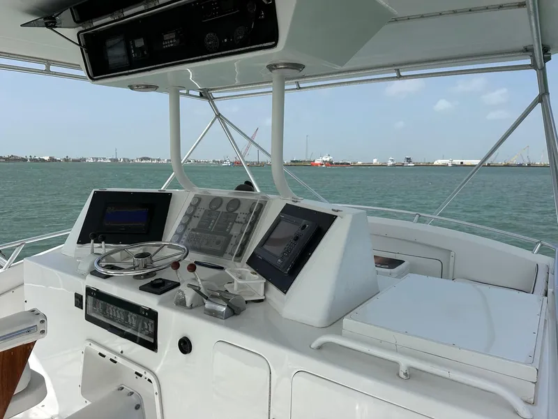 Slide: The Image of 1990 Bertram 50 Convertible yacht helm with modern navigation equipment on open water. - 5