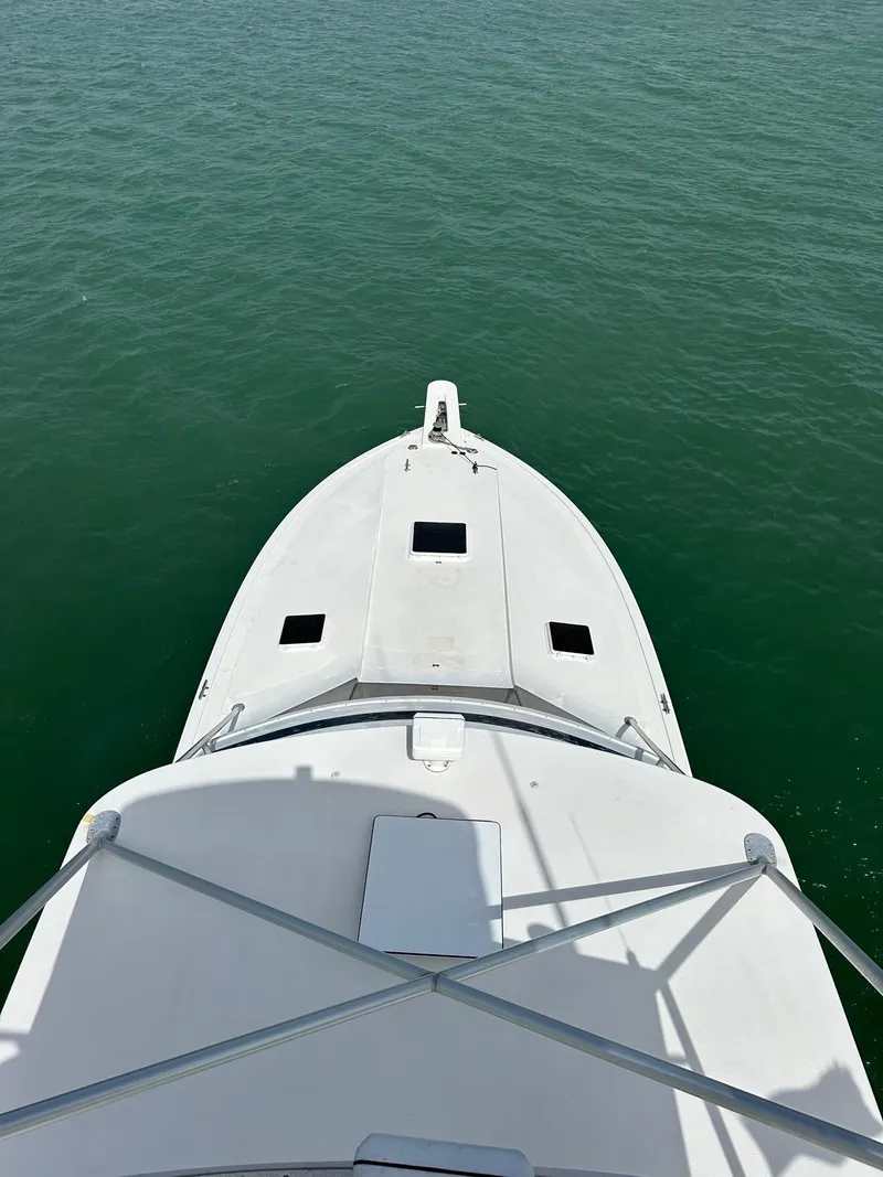 Slide: The Image of 1990 Bertram 50 Convertible yacht on calm green water, aerial view. - 9
