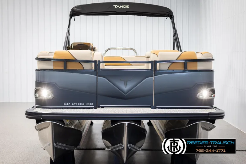 Slide: The Image of 2025 Tahoe SP Cr pontoon boat, rear view, in showroom with Reeder-Trausch Marine branding. - 8