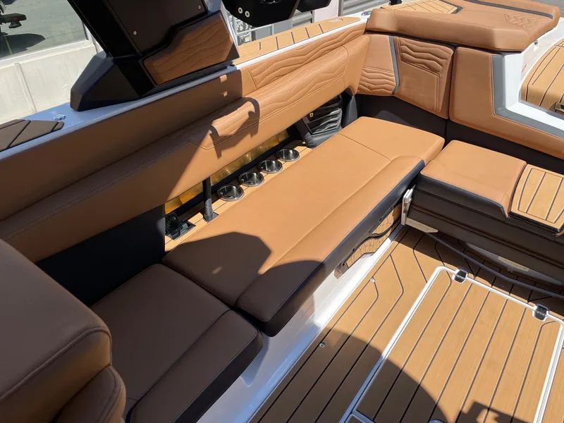 Slide: The Image of 2025 Nautique Super Air Nautique G25 interior with tan leather seating and cup holders. - 7