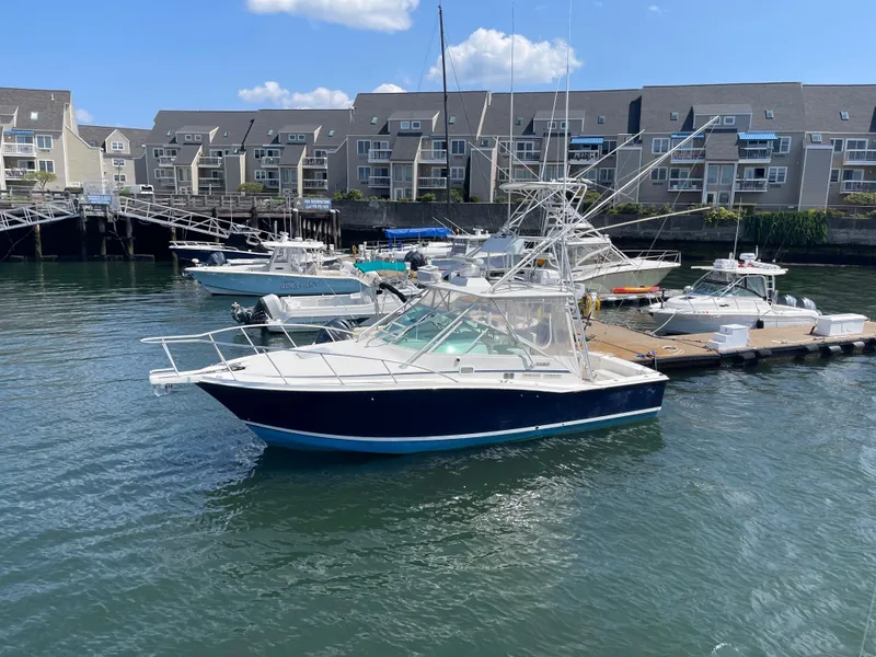 Slide: The Image of 1999 Cabo 31 Express boat docked in marina with waterfront buildings. - 0