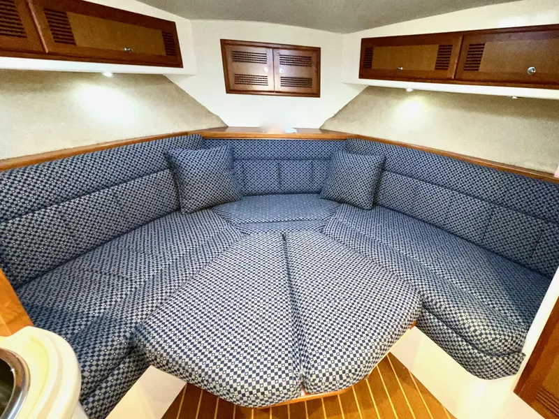 Slide: The Image of 1999 Cabo 31 Express cabin interior with blue patterned seating and wooden accents. - 10