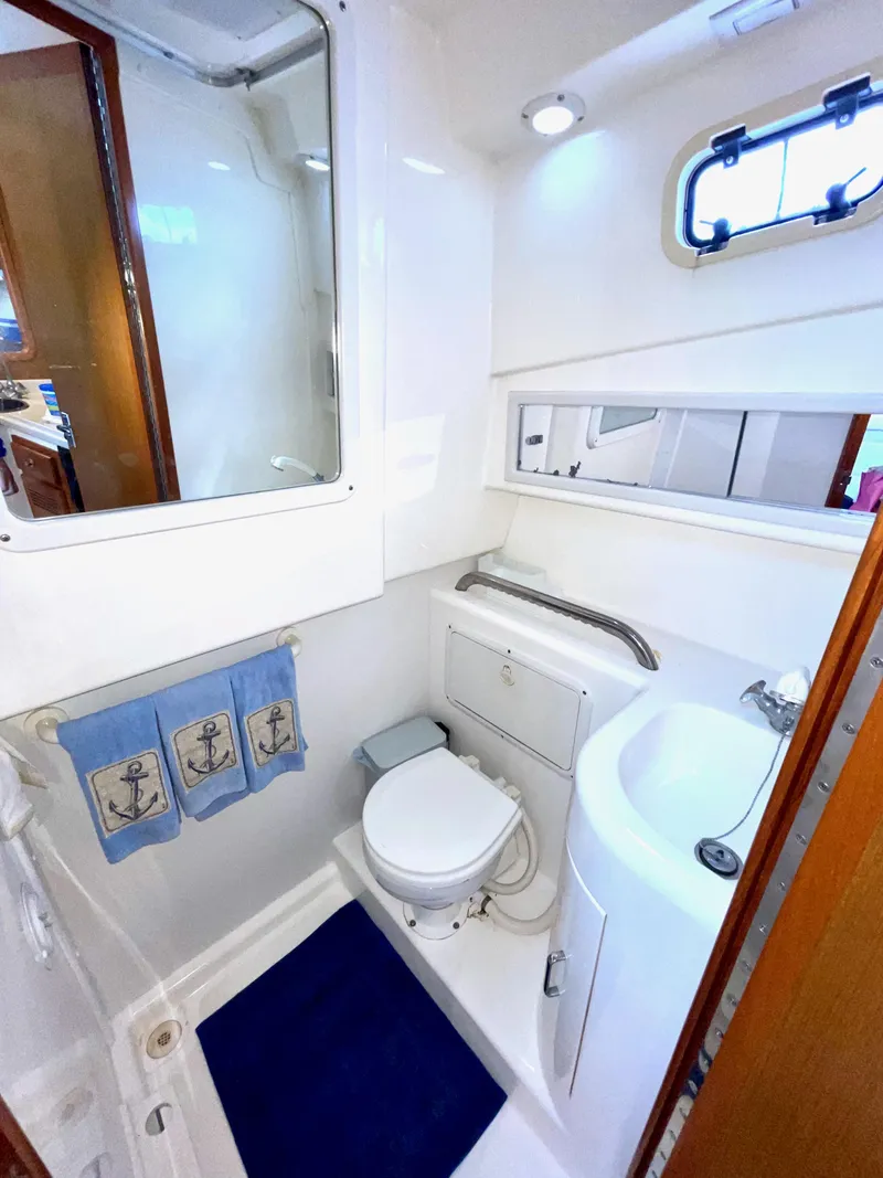 Slide: The Image of 1999 Cabo 31 Express boat bathroom with toilet, sink, and nautical-themed decor. - 11