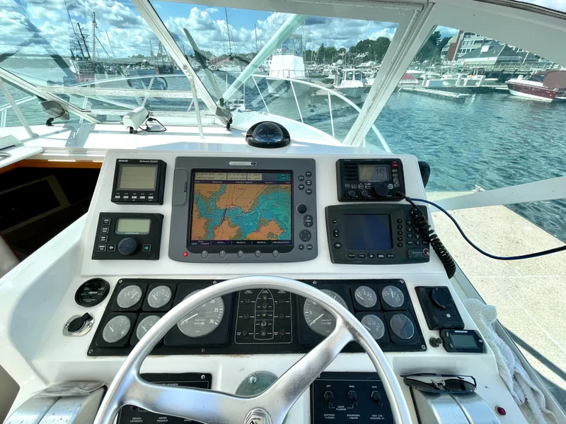 Slide: The Image of Helm of 1999 Cabo 31 Express boat with navigation equipment and scenic marina view. - 16