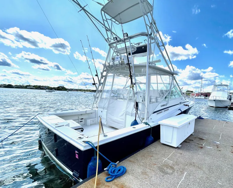 Slide: The Image of 1999 Cabo 31 Express boat docked by the water under a clear blue sky. - 17