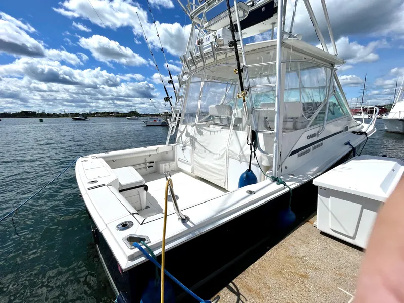 Slide: The Image of 1999 Cabo 31 Express boat docked under a partly cloudy sky. - 19