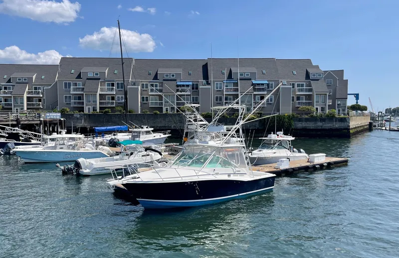 Slide: The Image of 1999 Cabo 31 Express boat docked in marina with waterfront buildings in background. - 22
