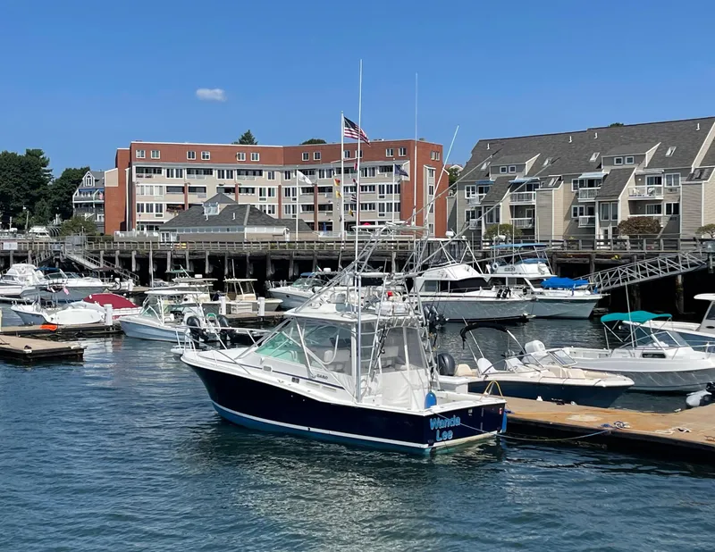 Slide: The Image of 1999 Cabo 31 Express boat docked in a marina with waterfront buildings in the background. - 23