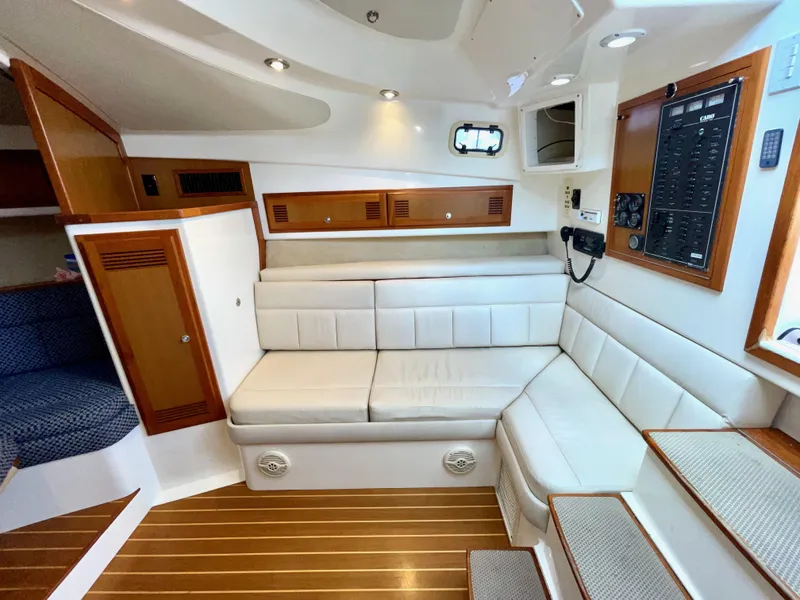Slide: The Image of Interior of a 1999 Cabo 31 Express boat with white seating and wooden accents. - 4