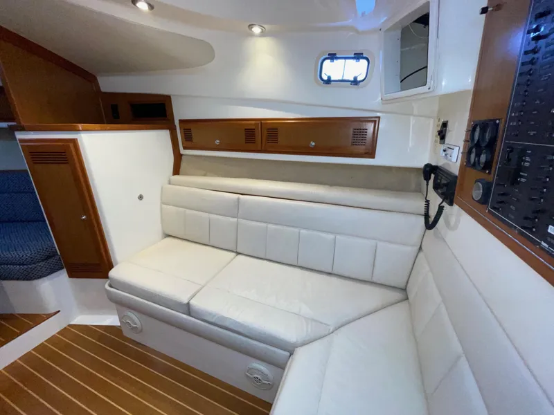 Slide: The Image of 1999 Cabo 31 Express cabin interior with white leather seating and wood accents. - 5