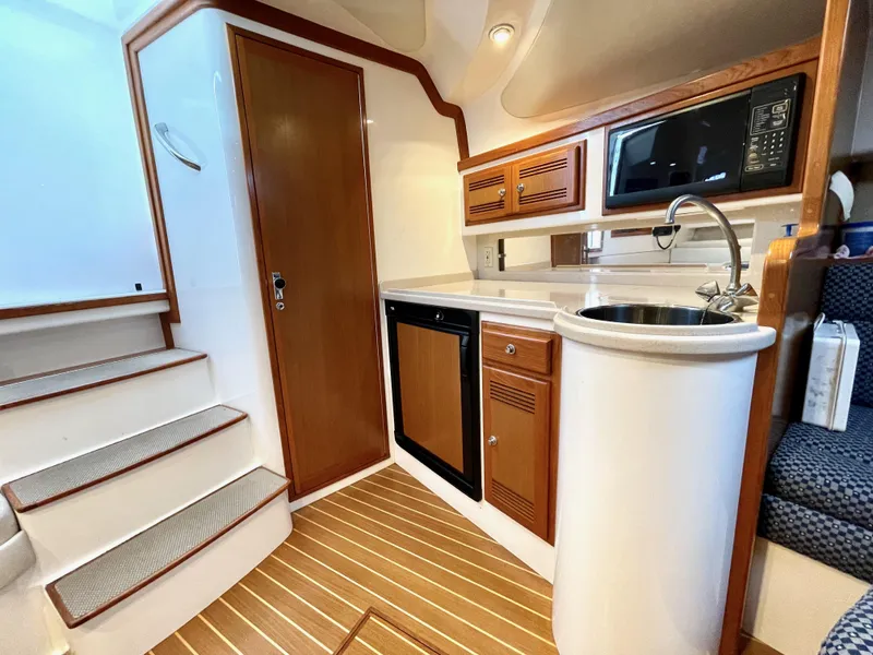 Slide: The Image of 1999 Cabo 31 Express yacht interior with kitchenette, featuring wood accents and modern appliances. - 8