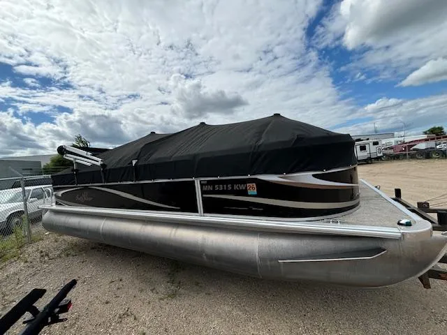 Slide: The Image of 2012 SunChaser 8522 C-N-F pontoon boat with black cover, parked on gravel. - 3