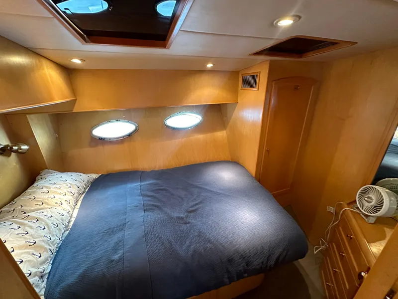 Slide: The Image of Cozy bedroom in 1999 McKinna 47 Sedan yacht with porthole windows and wooden interior. - 13