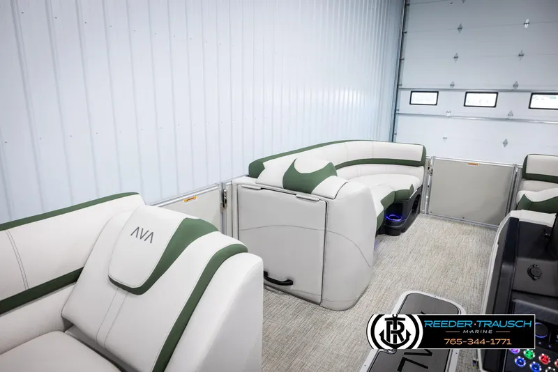 Slide: The Image of 2025 Avalon Catalina EL pontoon boat interior with white and green seating in a garage. - 21