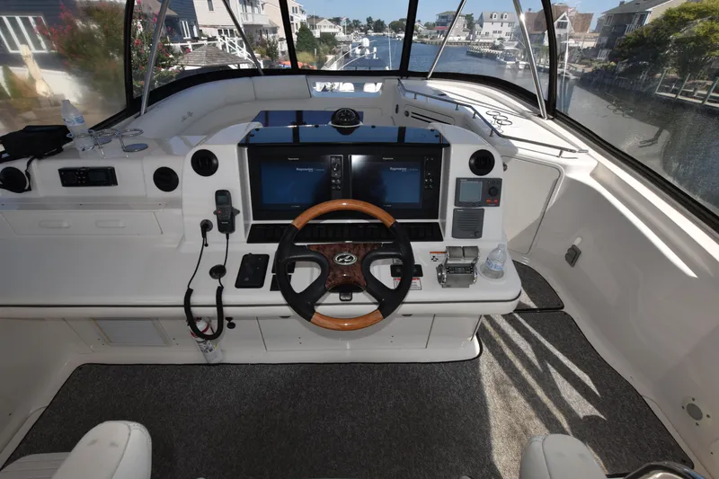 Slide: The Image of 2006 Sea Ray 58 Sedan Bridge helm with dual screens and wood-accented steering wheel. - 15