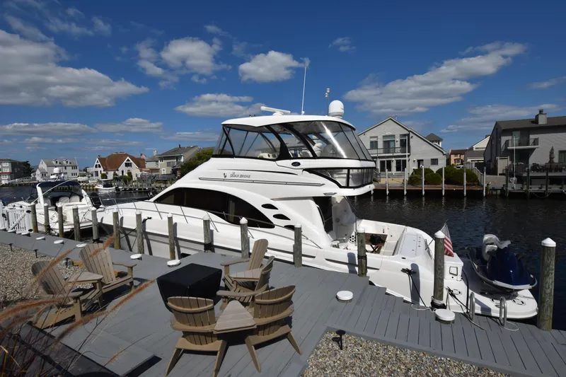 Slide: The Image of 2006 Sea Ray 58 Sedan Bridge yacht docked by waterfront homes under blue sky. - 4