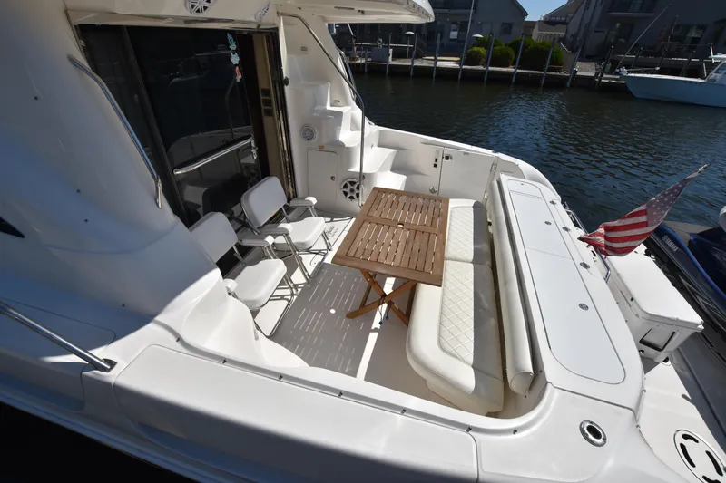 Slide: The Image of 2006 Sea Ray 58 Sedan Bridge yacht deck with seating and table, docked by the water. - 7