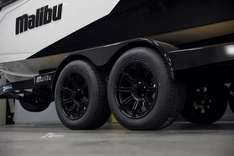 Slide: The Image of 2025 Malibu 23 LSV boat trailer with black wheels in a garage. - 6