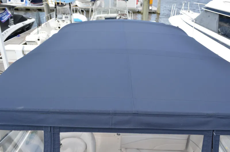 Slide: The Image of 2006 Larson Cabrio 240 boat with blue canvas top at marina. - 10