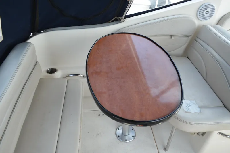 Slide: The Image of 2006 Larson Cabrio 240 boat interior with wooden table and white seating. - 12