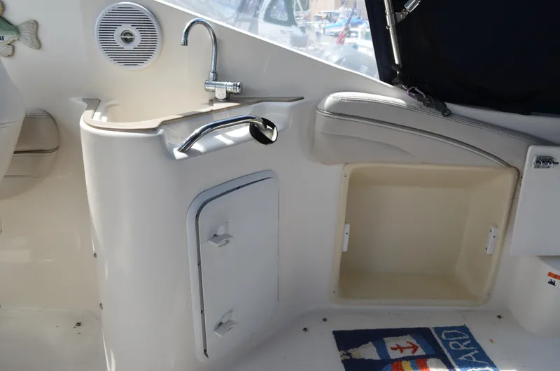 Slide: The Image of 2006 Larson Cabrio 240 boat interior with sink, storage, and nautical-themed mat. - 14