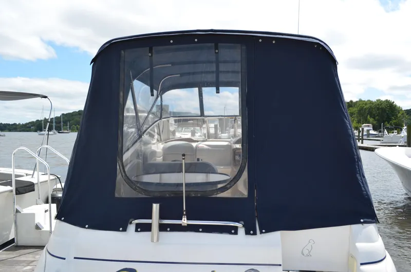 Slide: The Image of 2006 Larson Cabrio 240 boat with blue canvas cover at a marina. - 2