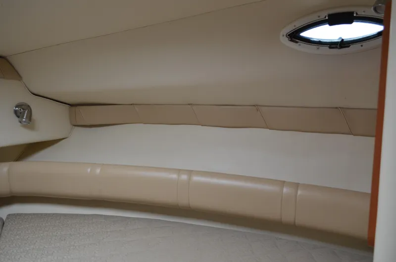 Slide: The Image of Interior cabin of 2006 Larson Cabrio 240 boat with beige upholstery and porthole. - 21