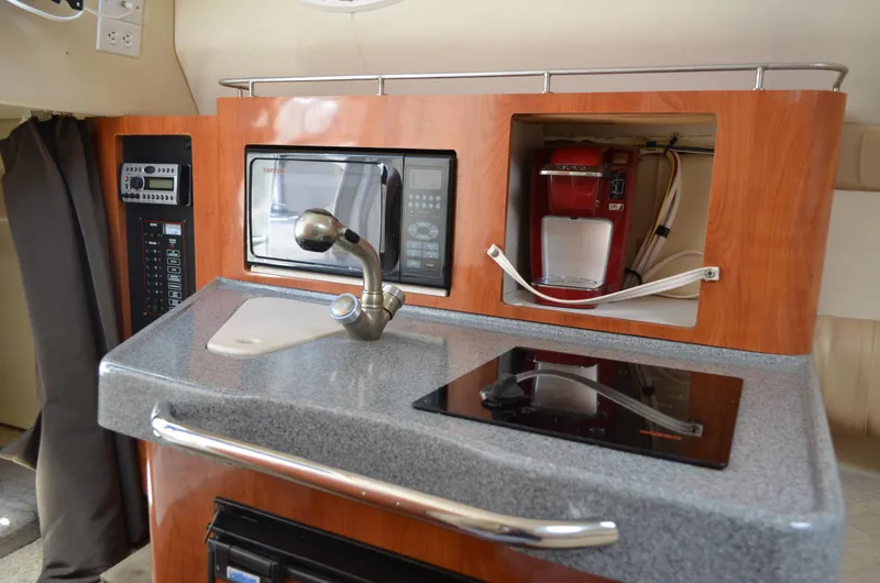 Slide: The Image of 2006 Larson Cabrio 240 boat kitchen with sink, microwave, coffee maker, and stove. - 25