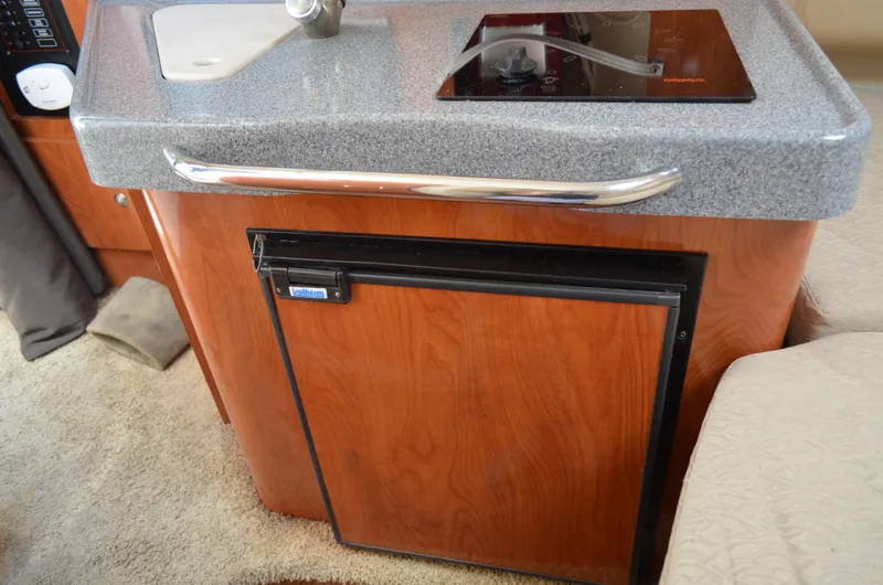 Slide: The Image of 2006 Larson Cabrio 240 interior with kitchenette, featuring a sink and mini fridge. - 27