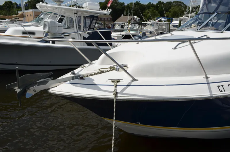 Slide: The Image of 2006 Larson Cabrio 240 boat docked at marina, featuring anchor and railing. - 6