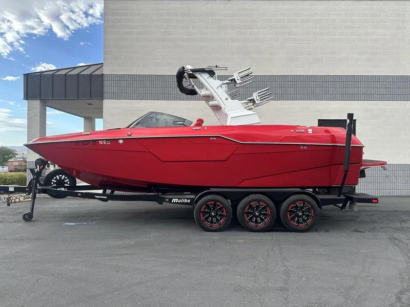 Slide: The Image of 2021 Malibu M240 red boat on trailer, parked outdoors. - 0