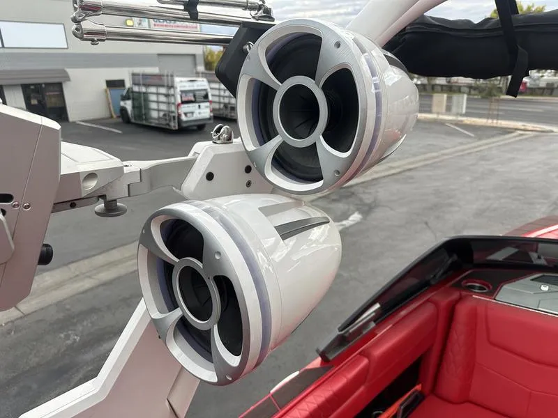 Slide: The Image of 2021 Malibu M240 boat speakers with red interior, parked outdoors. - 25